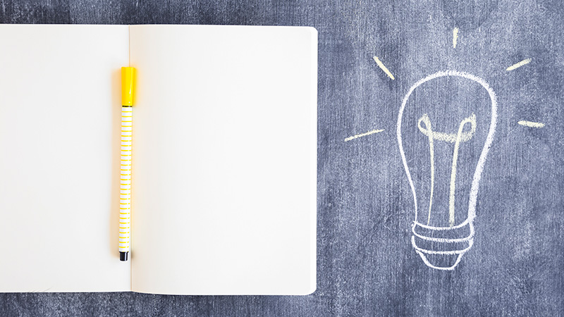 Principles-of-Agency-search-Explained open notebook with a pen next to a drawing of a light bulb on a chalkboard