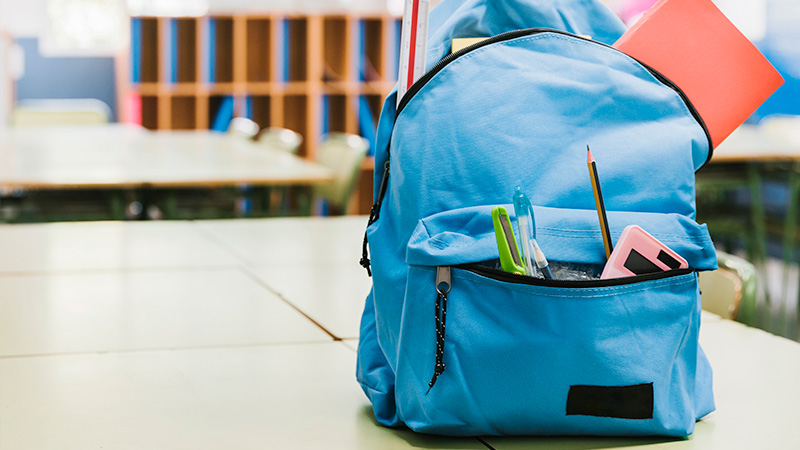 Blue bag pack on table with student stationery