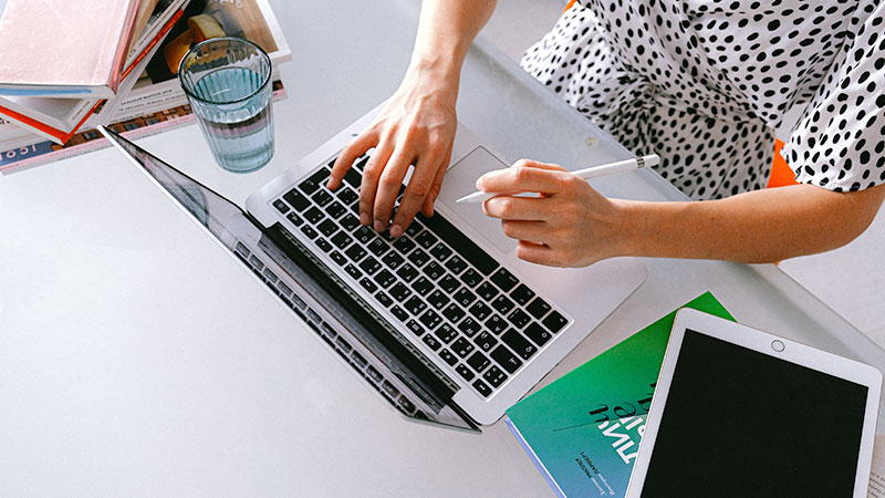 CMA-helps-2 Person holding a pencil typing on laptop computer