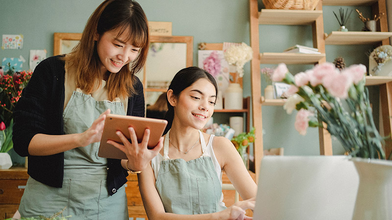 Two women in flower shop looking at computer screen