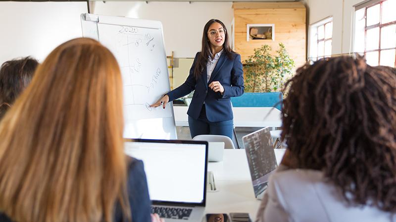 Talent-Council Woman in front of room giving presentation to her colleagues