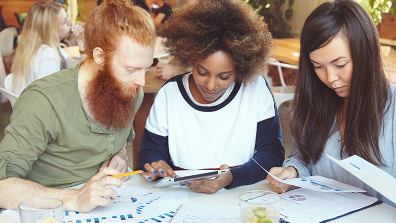 Diverse group of people at table analysing information on paper