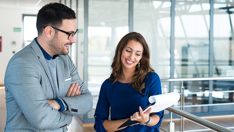 Membership-Benefits Woman showing man paper on clip board