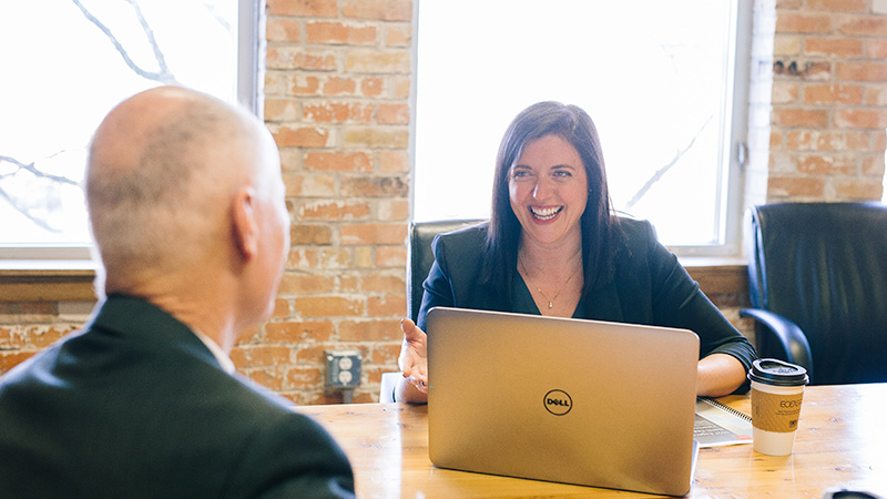 Woman with laptop computer open talking to man